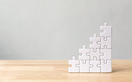 Jigsaw puzzle stacking as step stair on wooden table. Business concept for growth success processの写真素材