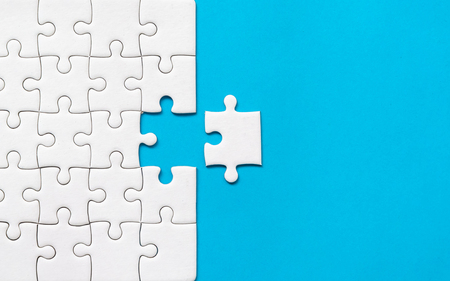 White jigsaw puzzle on blue background. Team business success partnership or teamwork.の写真素材