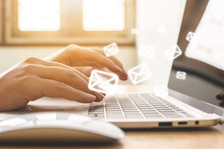 Email marketing and newsletter concept. Hand of man sending message and laptop with e-mail iconの写真素材