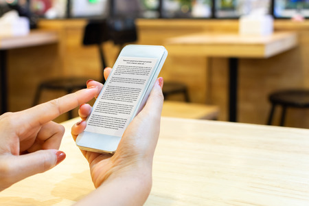 Woman reading an e-book online digital smartphone with application mobile deviceの写真素材