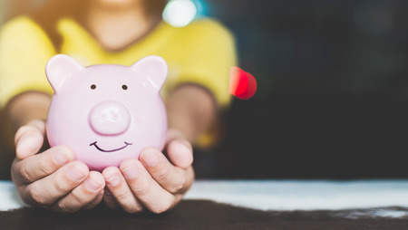 Female hand holding piggy bank. Save money and financial investmentの写真素材