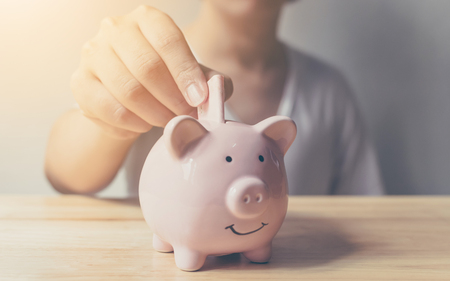 Young man hand putting banknote in piggy bank. Saving money concept finance business investmentの写真素材