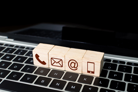 Wood block symbol telephone, mail, address and mobile phone on laptop keyboard. Website page contact us or e-mail marketing conceptの写真素材