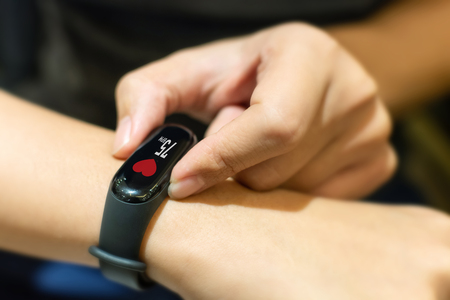 Close up image hand of male using smart watch with health app checking measure heart rate at normal levelsの写真素材