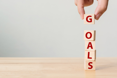 Hand putting wood cube with word GOALS. Concept of your business target or lifestyleの写真素材