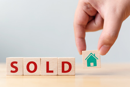 Hand holding wood cube block with icon house and word SOLD. Property investment and house mortgage financial conceptの写真素材