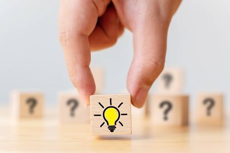 Concept creative idea and innovation. Hand picked wooden cube block with question mark symbol and...