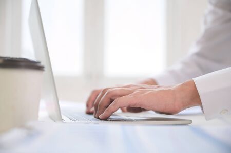 Close up image of businessman hands working computer laptop searching or typing text message for new...