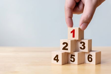 Hand arranging wood block stacking as step stair with number. The best excellent business services...