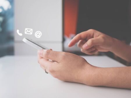 Woman hand using smart phone with icon telephone, email and address. Contact us connection conceptの写真素材
