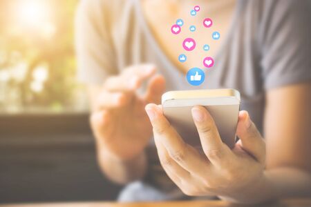 Woman hand using mobile smartphone with icon social media and social network. Online marketing conceptの写真素材