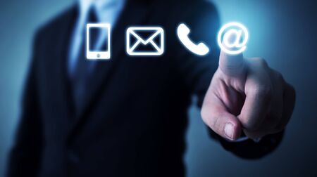 Businessman touching icon mobile phone, mail, telephone and address. Customer service call center contact us conceptの写真素材