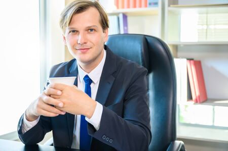 Portrait of young business man sitting at his desk in the office