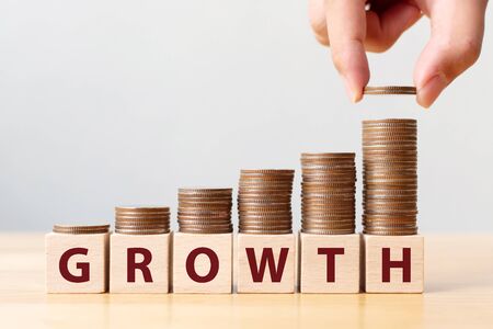 Hand putting coins on stack stair as step growing growth and wooden cube block with word GROWTH. Investment and save money increase conceptの写真素材
