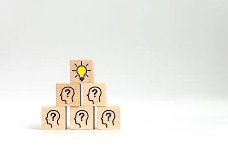 Concept creative idea and innovation. Wooden cube block with light bulb icon on top pyramid and head human symbolの写真素材