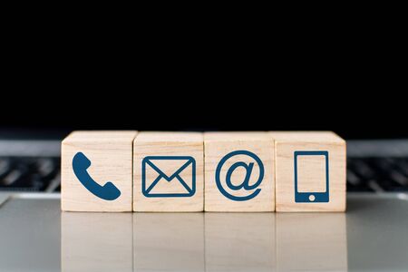 Wood block symbol telephone, mail, address and mobile phone on laptop keyboard. Website page contact us or e-mail marketing conceptの写真素材