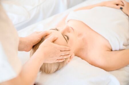 Beautiful woman receiving head and facial massage in spa salon. Concept of body health care and traditional thai massage relaxの写真素材