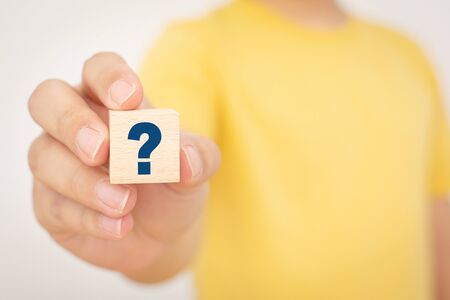 Hand holding wooden cube block shape with sign question mark symbolの写真素材