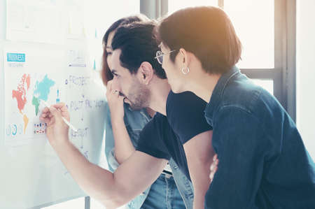 Business people meeting workshop at office and use notes to share idea. Brainstorming and teaching or coaching mentor concept. Paperwork document graph and diagram on whiteboard or flip chartの写真素材