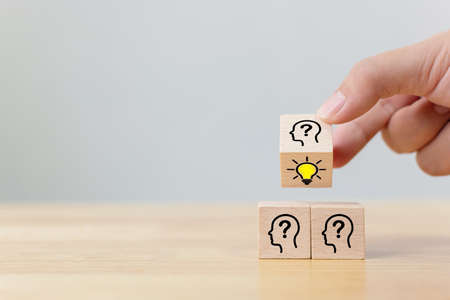 Concept creative idea and innovation. Hand flip over wooden cube block with head human symbol and light bulb iconの写真素材