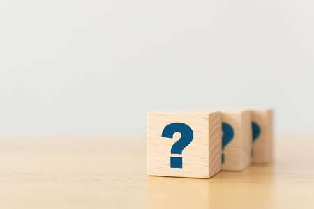 Wooden cube block shape with sign question mark symbol on wood tableの写真素材