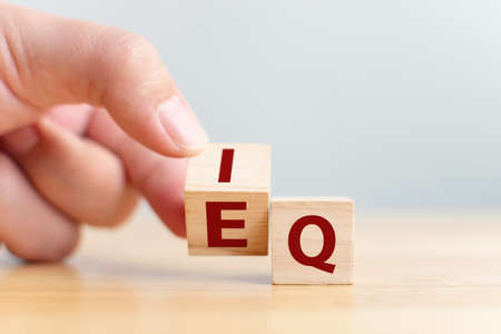 Hand flip wooden cube with word IQ to EQ. Emotional intelligence and intelligence quotientの写真素材