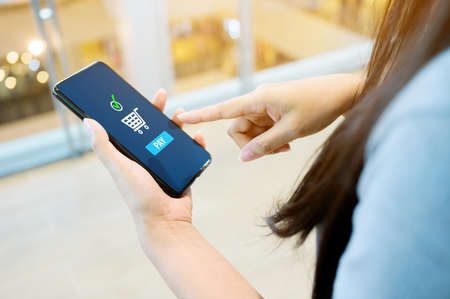 Concept online payment mobile technology. Hand of female using smartphone touching pay button mobile banking applicationの写真素材