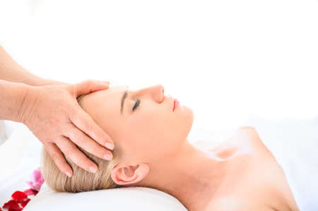 Beautiful woman receiving head and facial massage in spa salon. Concept of body health care and traditional thai massage relaxの写真素材