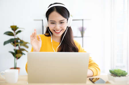 Young asian woman in headphone having conversation chatting while using laptop at house. Work at home, Video conference, Online meeting video call, Virtual meetings, Remote learning and E-learningの写真素材