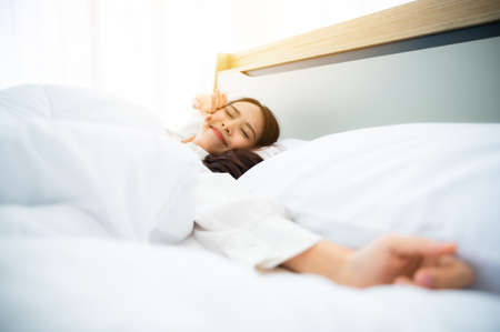 Beautiful women asian wake up in morning in bedroom. She is stretching and feeling freshの写真素材