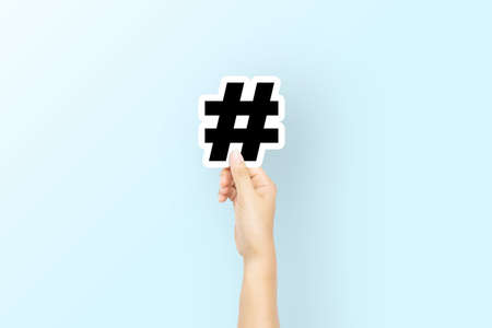 Hand holding paper with icon hashtag on light blue background