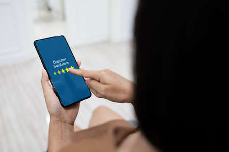 Customer review rating business concept, Woman hand using mobile phoneの写真素材