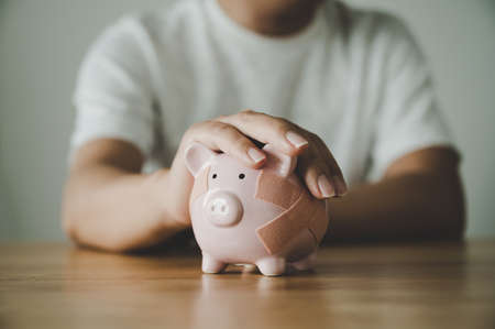 Man hand holding piggy bank on wooden table. Concept of save money and finance business investmentの写真素材