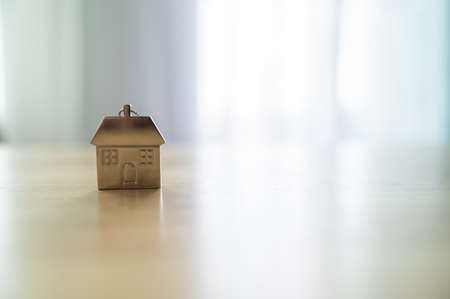 Keychain shaped house on wooden table in room. Property investment and house mortgage financial real estate conceptの写真素材