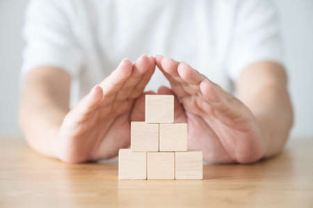 Hand of a man protecting wood blocks group on wood table