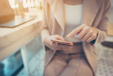 Close up hand of businesswoman using mobile smart phone. She working at cafe workplaceの写真素材