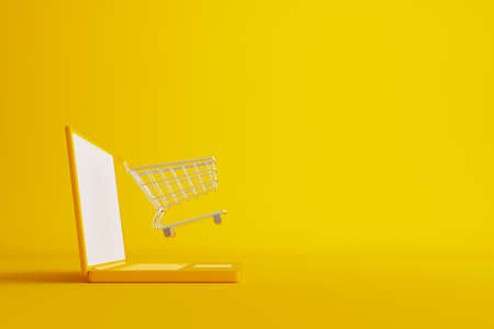 Online shopping and ecommerce concept. Web or mobile application e-commerce. Computer laptop with shopping cart on yellow background. 3d rendering illustrationの写真素材