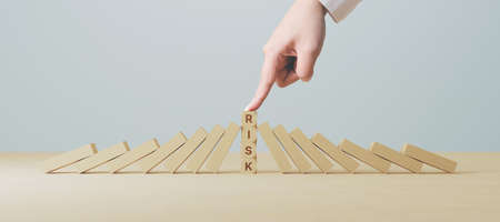 Risk management concept. Hand stop wooden block domino effect for businessの写真素材