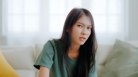 Upset asian woman frustrated by problem with work or relationships, sitting on couch, feeling despair and anxiety, loneliness, having psychological troubleの写真素材