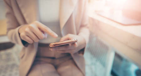 Close up hand of businesswoman using mobile smart phone. She working at cafe workplaceの写真素材