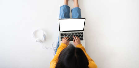 Top view of woman sitting on floor and using laptop blank screen white background. Mockup, template for your text, Clipping paths included for device screen. Panoramic image with empty copy spaceの写真素材