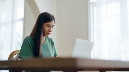 Young asian woman working at home. Female using computer laptop on desk at houseの写真素材