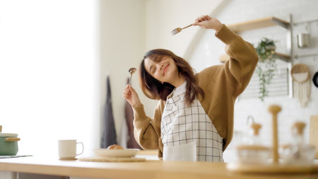 Asian young woman dancing in kitchen room. She happy and relaxing at free time on weekendの写真素材