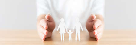 Hand protecting family on wood table. Healthcare and life insurance conceptの写真素材