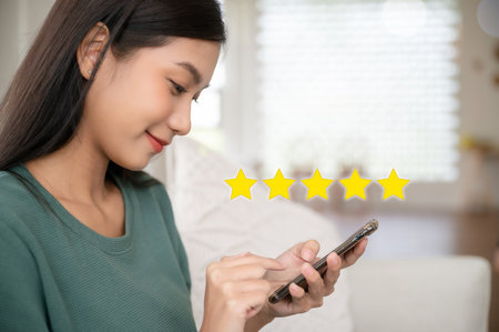 Customer service experience and business satisfaction survey. Woman hand using smart phone with icon five star symbol to increase rating of company conceptの写真素材