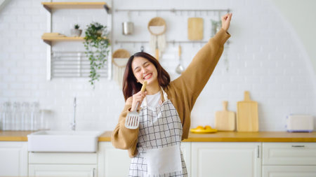 Asian young woman dancing in kitchen room. She happy and relaxing at free time on weekendの写真素材