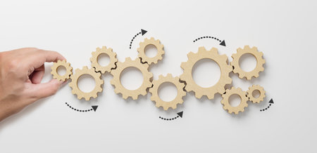 Business process and workflow automation with flowchart. Hand holding wooden cog flowing process management on white backgroundの写真素材