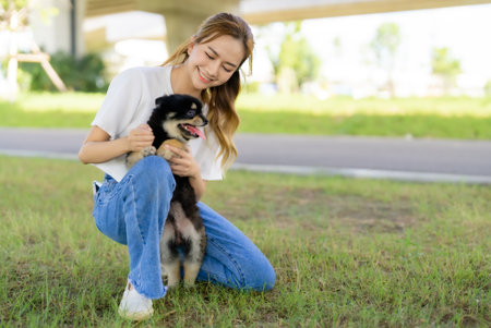 Happy young asian woman playing and sitting on grass in the park with her dog. Pet lover conceptの写真素材