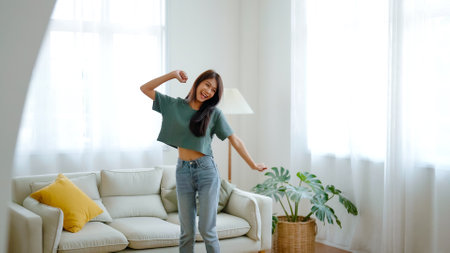 Young asian woman dancing on the floor in living room at home. Happy asia female smile relaxing in house, healthy mental wellness and wellbeingの写真素材