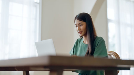 Young asian woman working at home. Female using computer laptop on desk at houseの写真素材